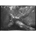 219052PD: Woman seated on tree trunk with book