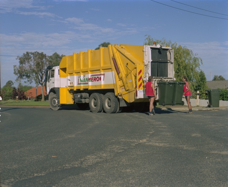 A City of Wanneroo rubbish truck empties wheelie bins at a kerbside, 20