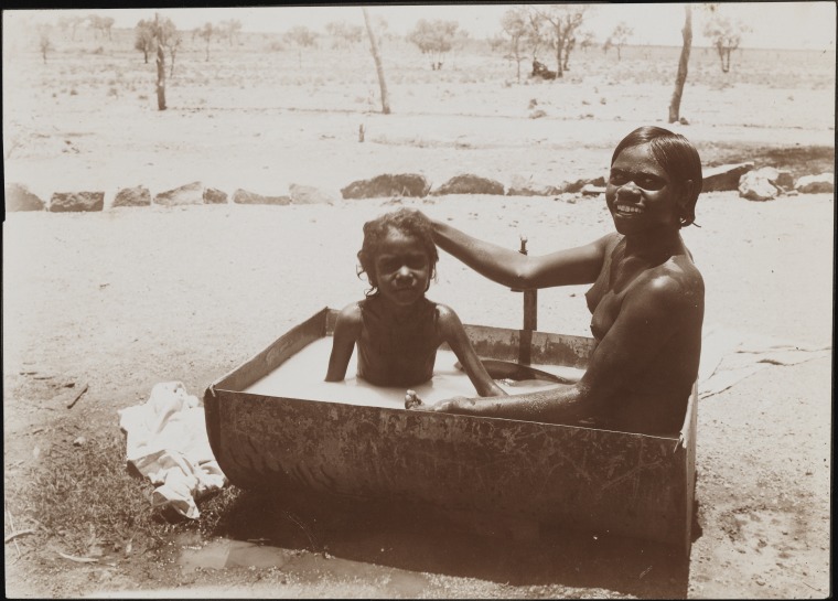 Aboriginal woman and child bathing in a halfdrum, possibly Njamal